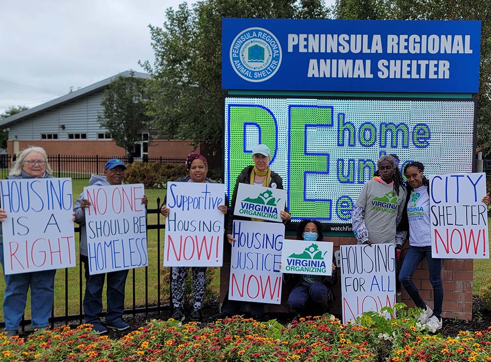 Picture of 7 chapter members holding signs about housing and homelessness in front of the marquis for the Peninsula regional animal shelter