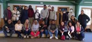 Photo of a diverse group of 23 people standing and sitting together smiling